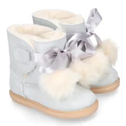 Botitas tipo Australianas niña con diseño con POMPONES en piel serraje metalizado.