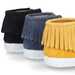 Botita tipo bamba con cordones y flecos en piel serraje en colores de temporada.