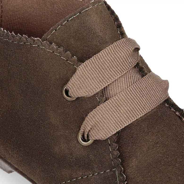 Botín tipo blucher con ondas y lazos en piel serraje.