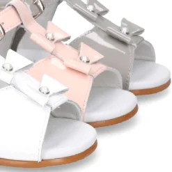Sandalia peques en forma de T con dos lazos y perlas en piel charol.