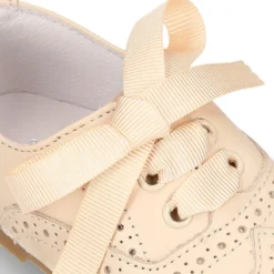 Zapatito tipo Blucher con lazo y picados en piel suave y colores dulces.