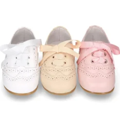 Zapatito tipo Blucher con lazo y picados en piel suave y colores dulces.