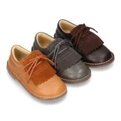 Zapatito tipo blucher con lengüeta con flecos y picados en piel combinada.