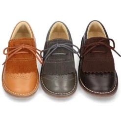 Zapatito tipo blucher con lengüeta con flecos y picados en piel combinada.