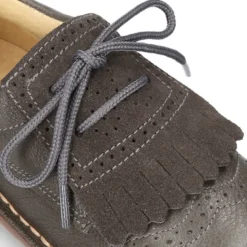 Zapatito tipo blucher con lengüeta con flecos y picados en piel combinada.