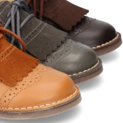 Zapatito tipo blucher con lengüeta con flecos y picados en piel combinada.
