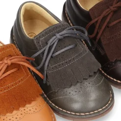 Zapatito tipo blucher con lengüeta con flecos y picados en piel combinada.