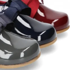 Zapatito tipo Blucher niño en piel charol con lazos.